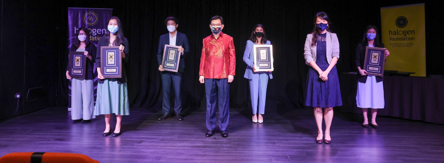 People on stage holding framed awards with a "halogen foundation" banner in background.